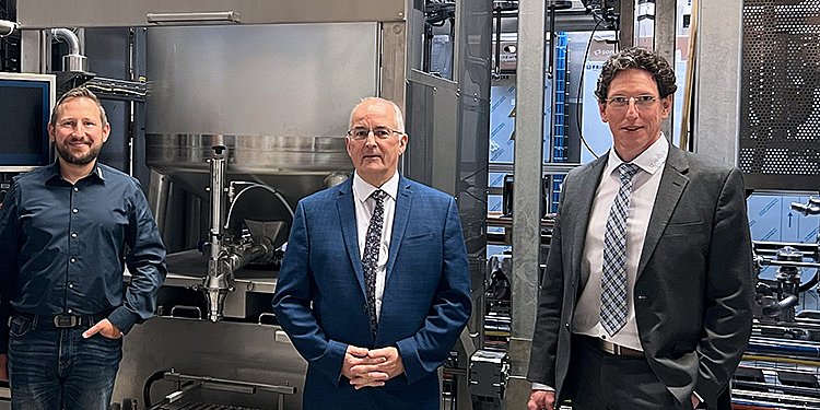 Die Gruppe von vier Männern steht lächelnd vor der FRICKE-Multiplex-Anlage in Minden.