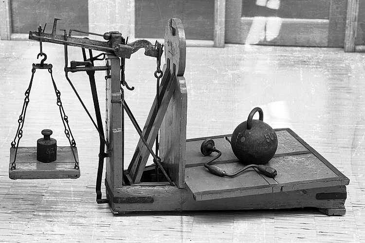 An old scale made of wood and metal, equipped with weights.