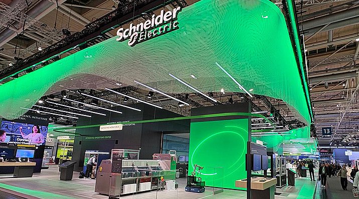 Der auffällige Stand von Schneider Electric mit leuchtend grüner Beleuchtung zieht die Aufmerksamkeit der Messebesucher auf sich.