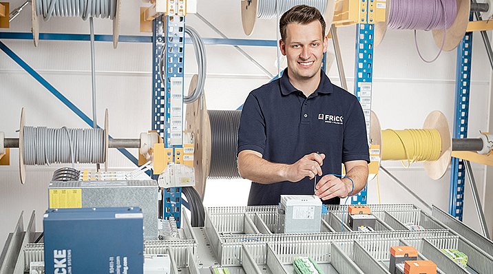 Umgeben von Kabelrollen und elektrischen Komponenten arbeitet ein Servicemitarbeiter von Fricke in der Werkstatt im Rahmen des Remote Service.