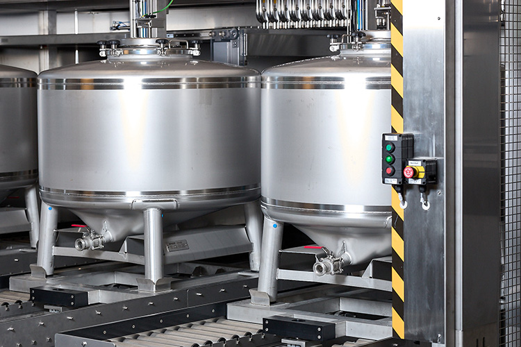 In einer modernen Produktionsstätte sind zwei Edelstahlbehälter sichtbar, die präzise für die Dosierung von Rohstoffen konzipiert sind.