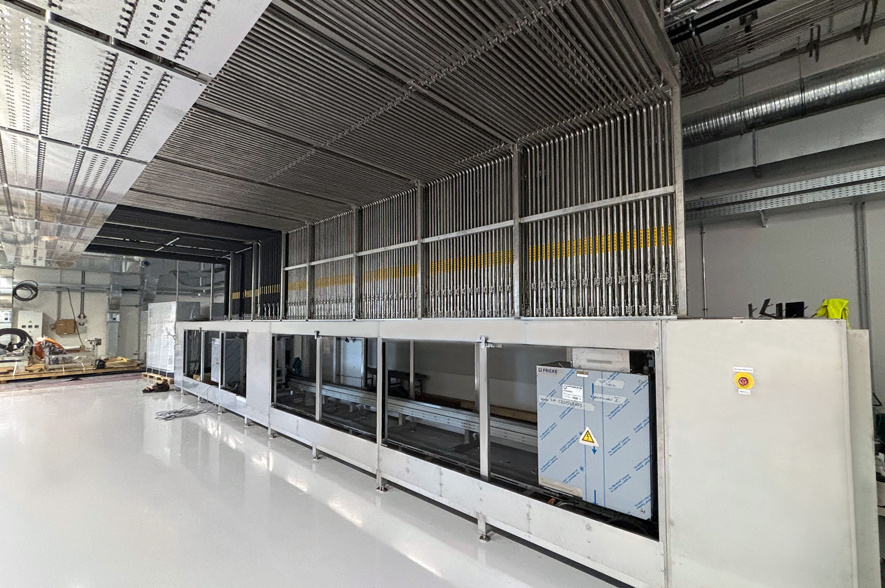 Die Innenansicht einer Fabrik zeigt eine komplexe Dosiereinheit mit glänzendem Boden und industrieller Ausstattung.