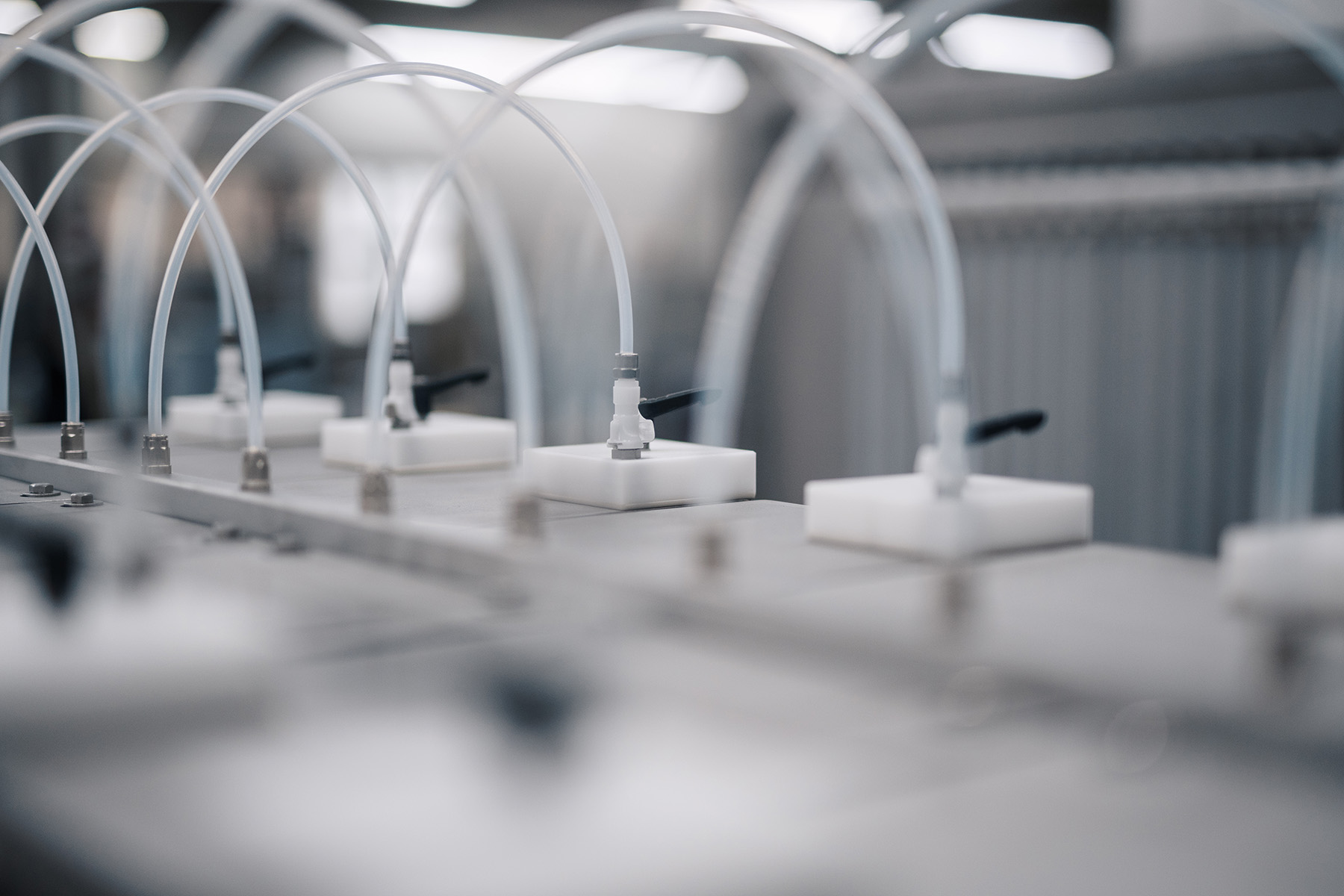 Ein modernes Dosiersystem mit weißen Halterungen und transparenten Schläuchen, das in einer sauberen, industriellen Umgebung installiert ist.