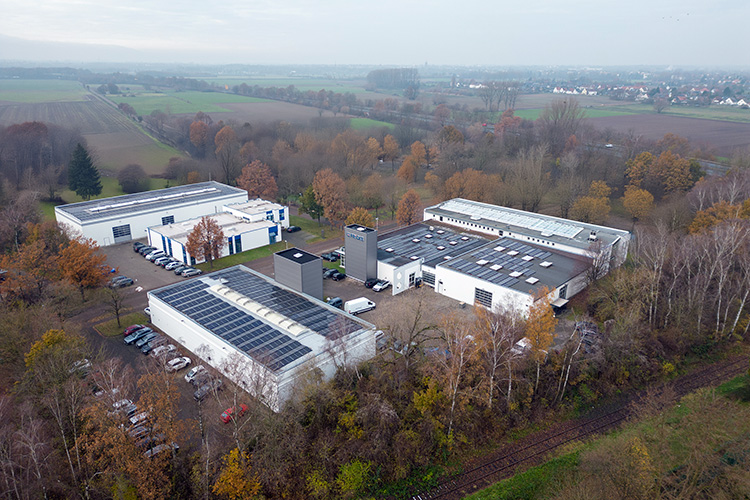 Aerial view of the FRICKE company building with multiple halls, surrounded by autumnal trees and fields.